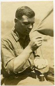 Soldier Using a Needle and Thread to Repair a Sock